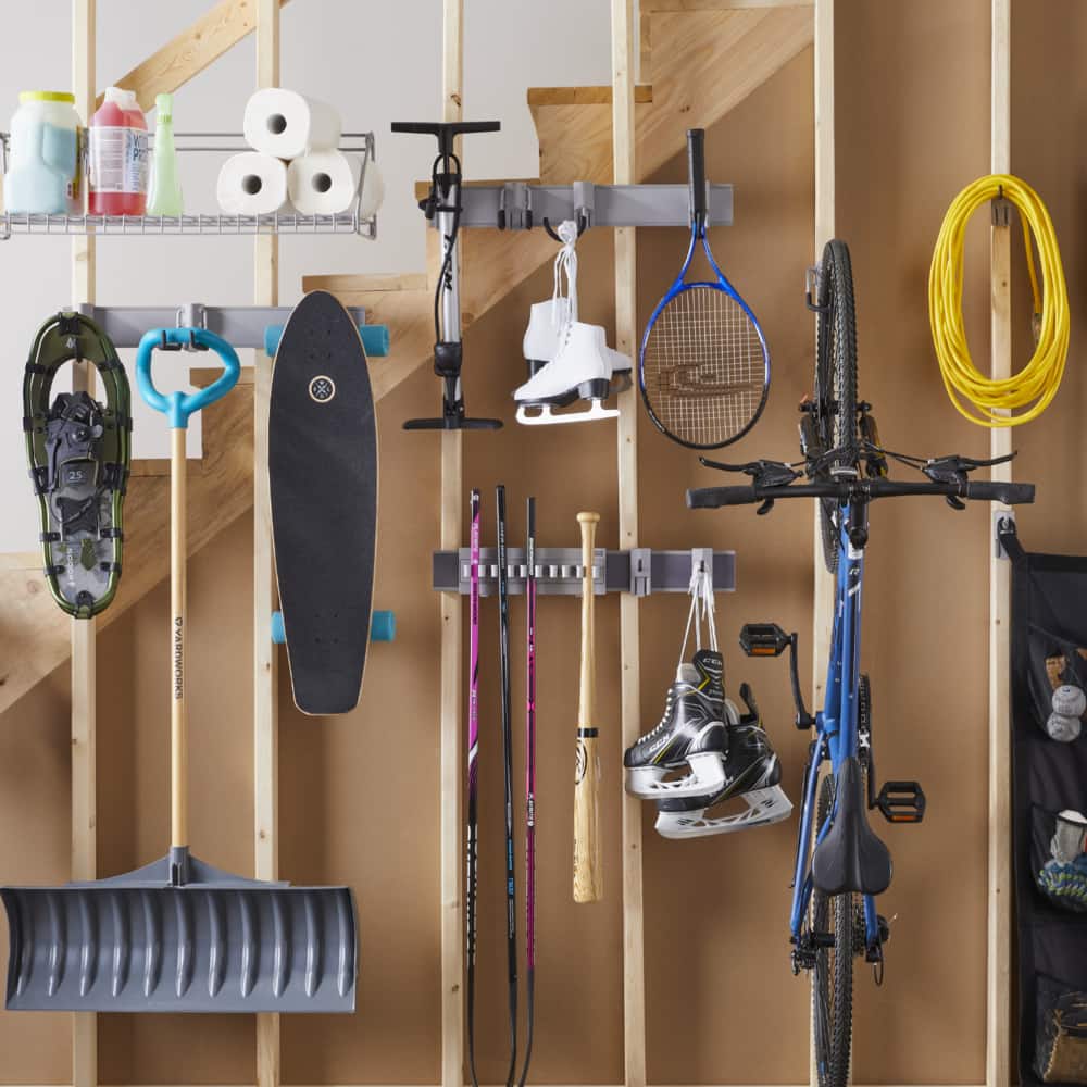 The Mastercraft MOD™ system installed on an unfinished basement wall with racks, holders, and hooks holding sports gear and cleaning supplies.