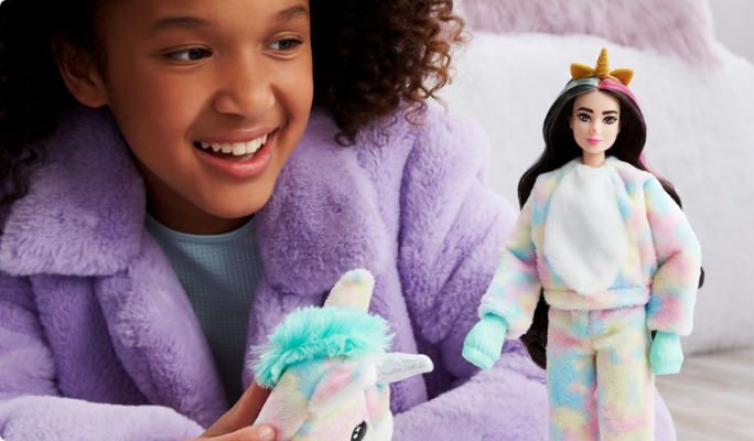 Girl in purple sweater playing with fluffy unicorn and unicorn Barbie.