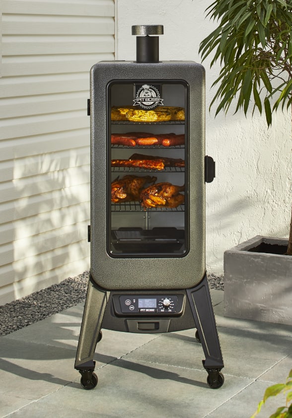 Fumoir numérique à granules de bois Pit Boss série 3 sur une terrasse avec viande à l'intérieur.