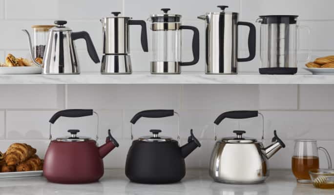 French press, kettles, espresso machine on kitchen counter and shelves. 