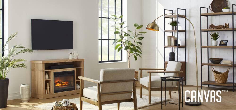Salon décoré avec des fauteuils d'appoint CANVAS, une bibliothèque, une lampe sur pied et un meuble pour téléviseur avec foyer électrique.