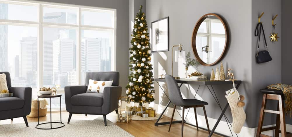 Décorations pour petits espaces NOMA dans une maison moderne, y compris un arbre mince illuminé et d’autres décorations de Noël au thème doré.