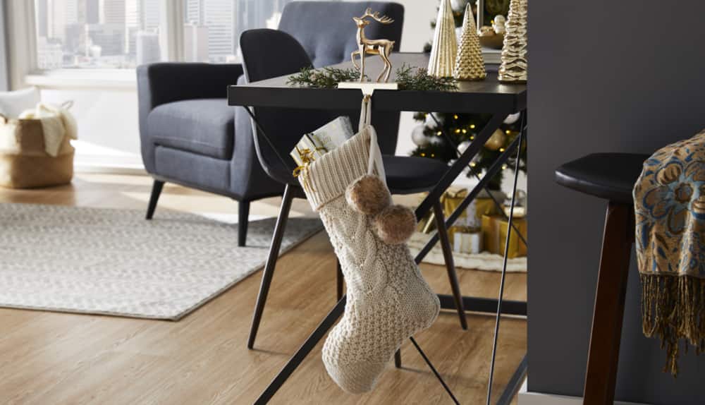 Bas de Noël en tricot à maille torsadée Canvas de couleur avoine suspendu à un dessus de table dans une maison.