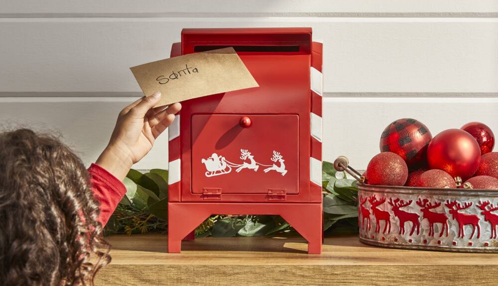 Young girl placing a santa letter in the CANVAS tabletop metal mailbox