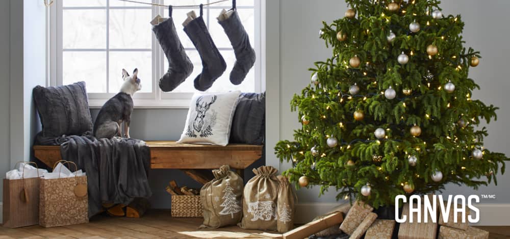 Coin vitré d’une maison décoré d’un arbre de Noël et de décorations de Noël de source soigneusement choisie, y compris des bas de Noël, une couverture, des ornements, des sacs-cadeaux et plus encore.