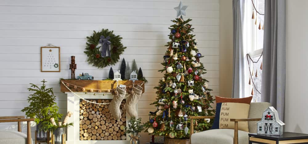 Une collection de décorations de Noël comprenant des ornements pour sapin, des bas de Noël, des pots décoratifs, une couronne et plus encore devant une cheminée.
