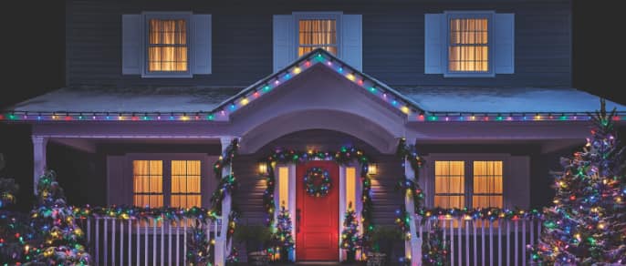Guirlandes lumineuses de Noël colorées NOMA décorant l’entrée d’une maison.