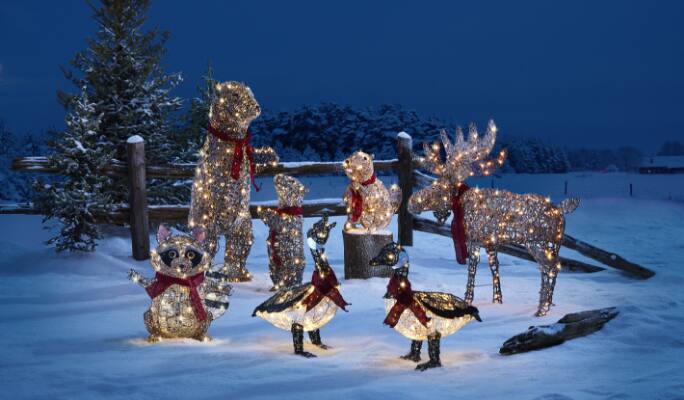 CANVAS pre-lit wireform lawn decorations of animals set on a snowy background.