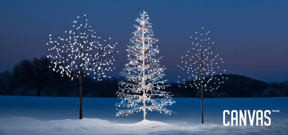 A range of CANVAS Outdoor Pre-Lit Trees on a snowy lawn including the Blossom Tree, Twig Tree, and Winter Forest Tree.