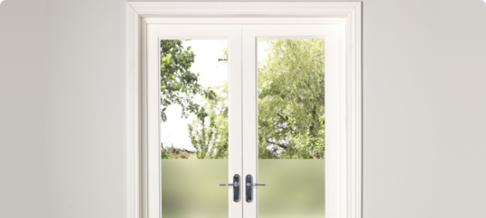A pair of French doors and doorframe painted white, leading to a yard.