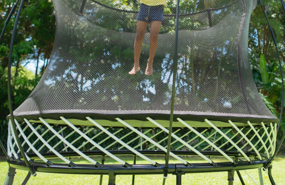 Un enfant qui saute sur un trampoline dans une cour.