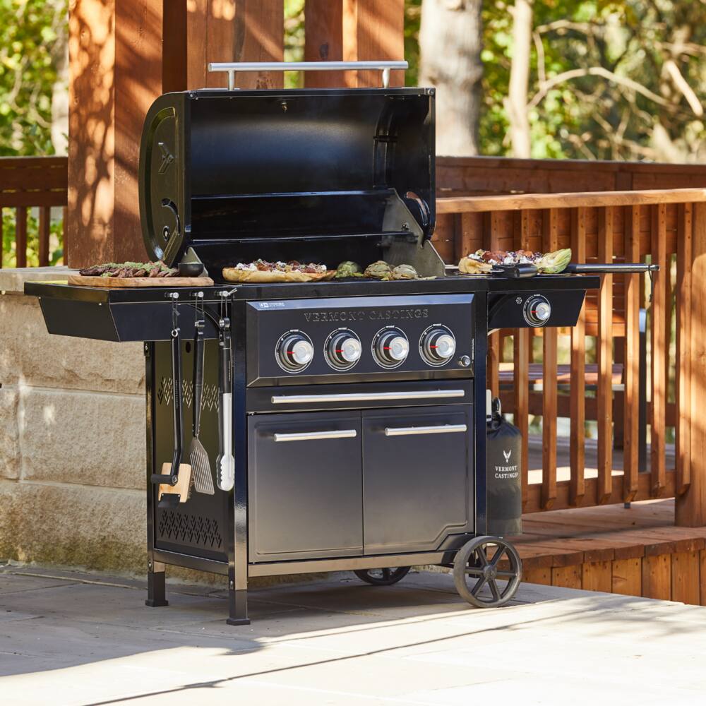 Vermont Castings Vanguard™ 4-Burner BBQ Grill open outdoors, grilling meat. 