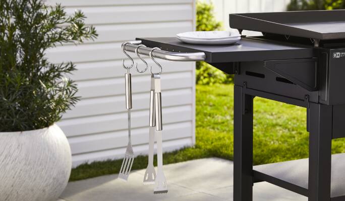 BBQ utensils hanging on MASTER Chef® Grill Turismo 4-Burner Griddle side shelf. 