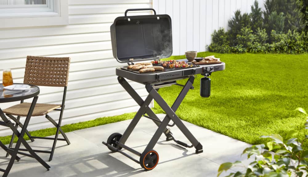 MASTER Chef® Portable BBQ in backyard grilling hot dogs and skewers.