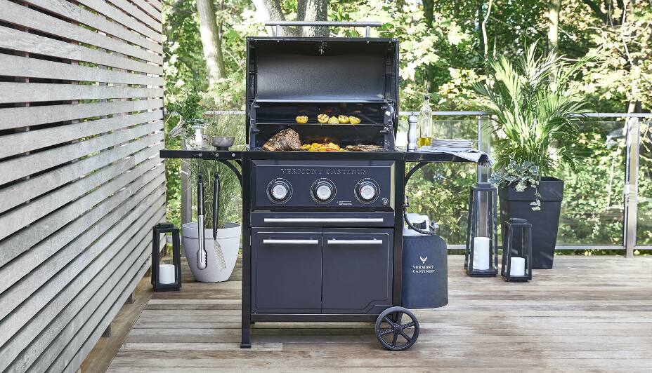 Un barbecue au propane noir et argenté Weber Spirit à 3 brûleurs sur une terrasse de jardin.
