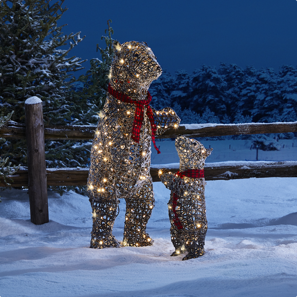 Two CANVAS Canadian Cabin bear Christmas figures lit up on a snowy lawn