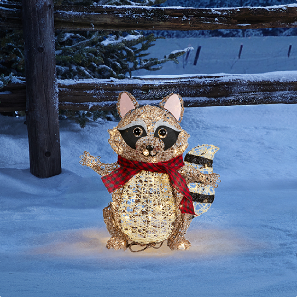 CANVAS Canadian Cabin raccoon figure lit up on a snowy lawn