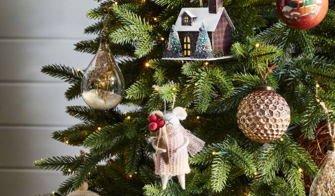 Vue rapprochée d’un arbre de Noël illuminés de lumières à DEL et décoré d’ornements fantaisistes.
