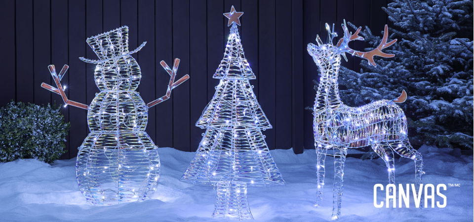 Lit-up Iridescent snowman, tree, and deer wireforms on a snowy lawn.
