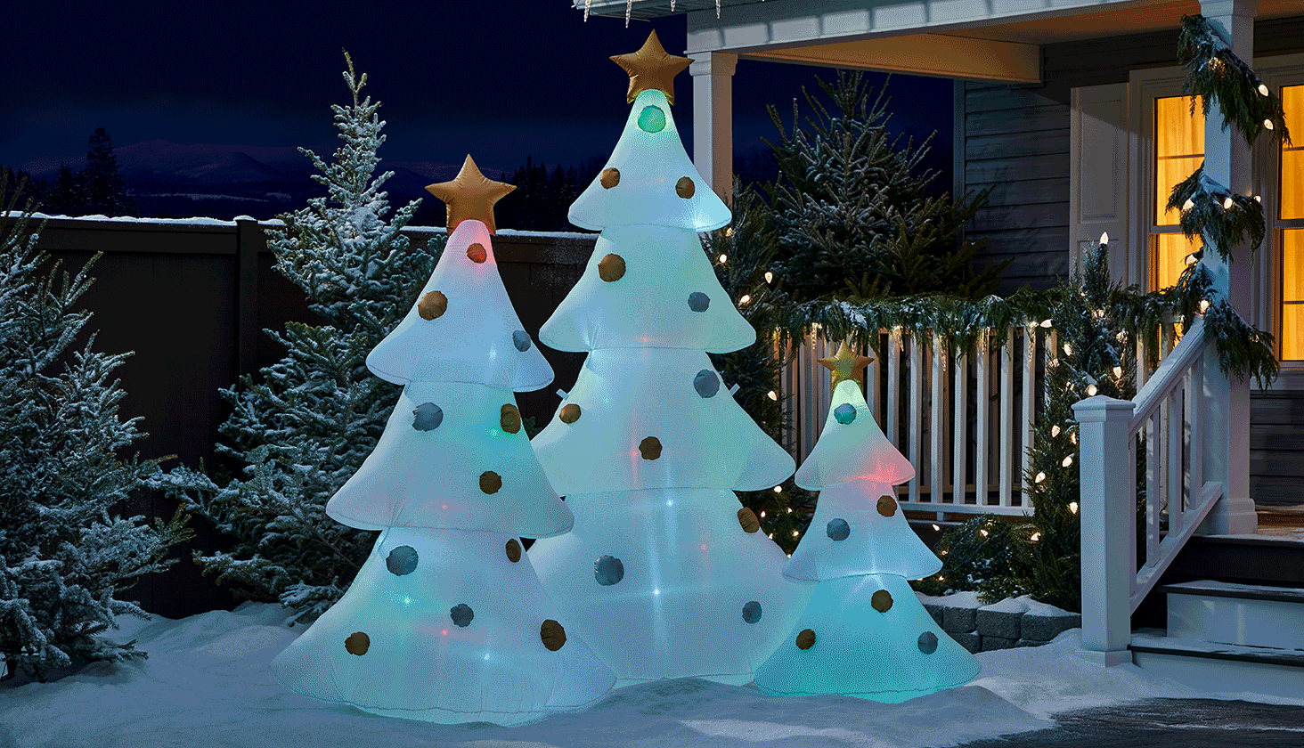 NOMA Advanced Smart 2.0 Christmas trees, 4-ft, 6-ft, 8-ft, on a snowy front lawn.