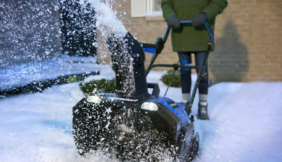 Person removing snow off their driveway with a cordless snowblower.
