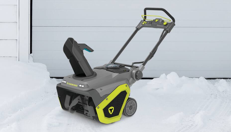 Product shot of Yardworks Stage Cordless Snowblower on a snowy driveway in front of a garage door. 