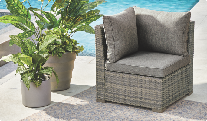 CANVAS Bala Corner Seat set up on a poolside patio with plush cushions and potted plants. 
