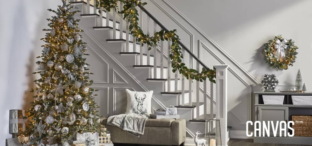A foyer of a home decorated with items from the CANVAS Silver Collection including the Normandy Fit Tree, ornaments, a garland, and more.
