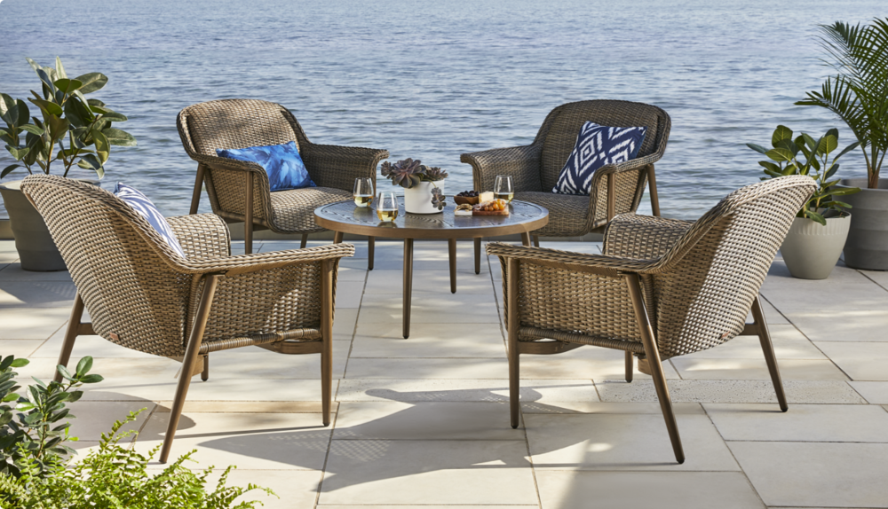 4 patio chairs and coffee table set up by the water. 