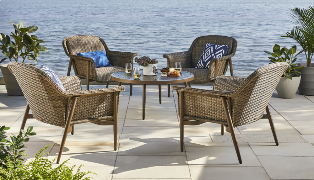 Quatre chaises et une table basse de jardin installées près de l’eau.