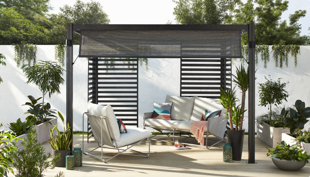 Outdoor gazebo with loveseat and armchair in backyard. 