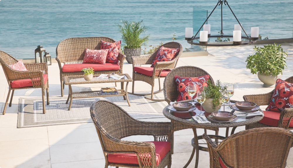 Outdoor loveseats and armchairs with red cushions.