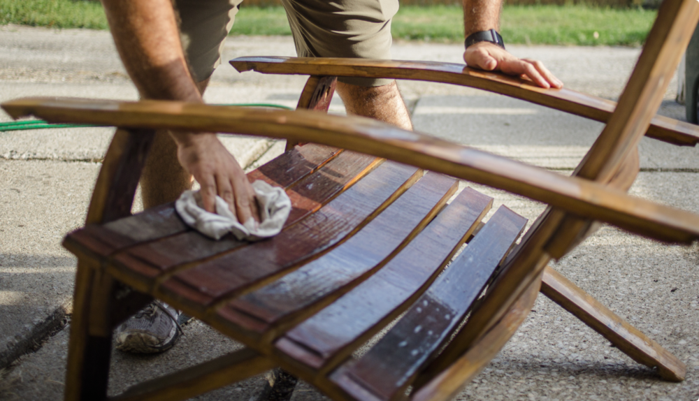 Man cleaning patio chair with cloth. 