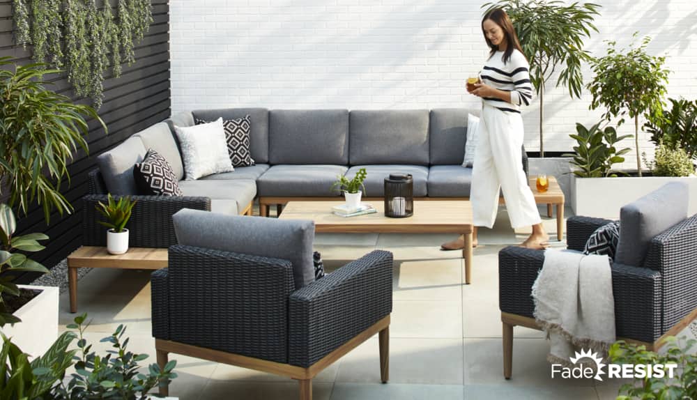 Woman on her patio with CANVAS Edenvale Sectional, club chairs and a coffee table. 