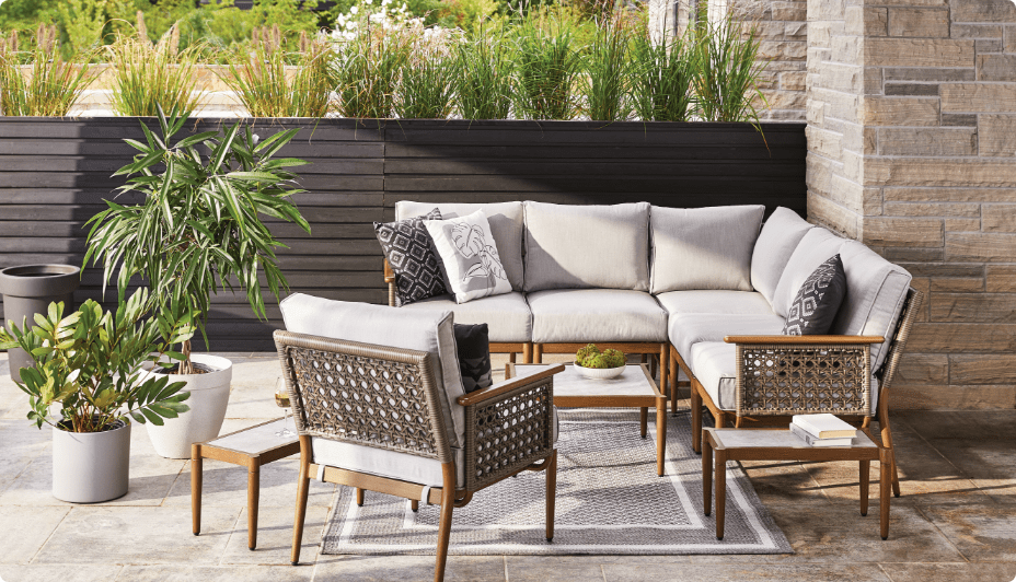 CANVAS Baffin Sectional set up on an outdoor patio with a rug and potted plants.
