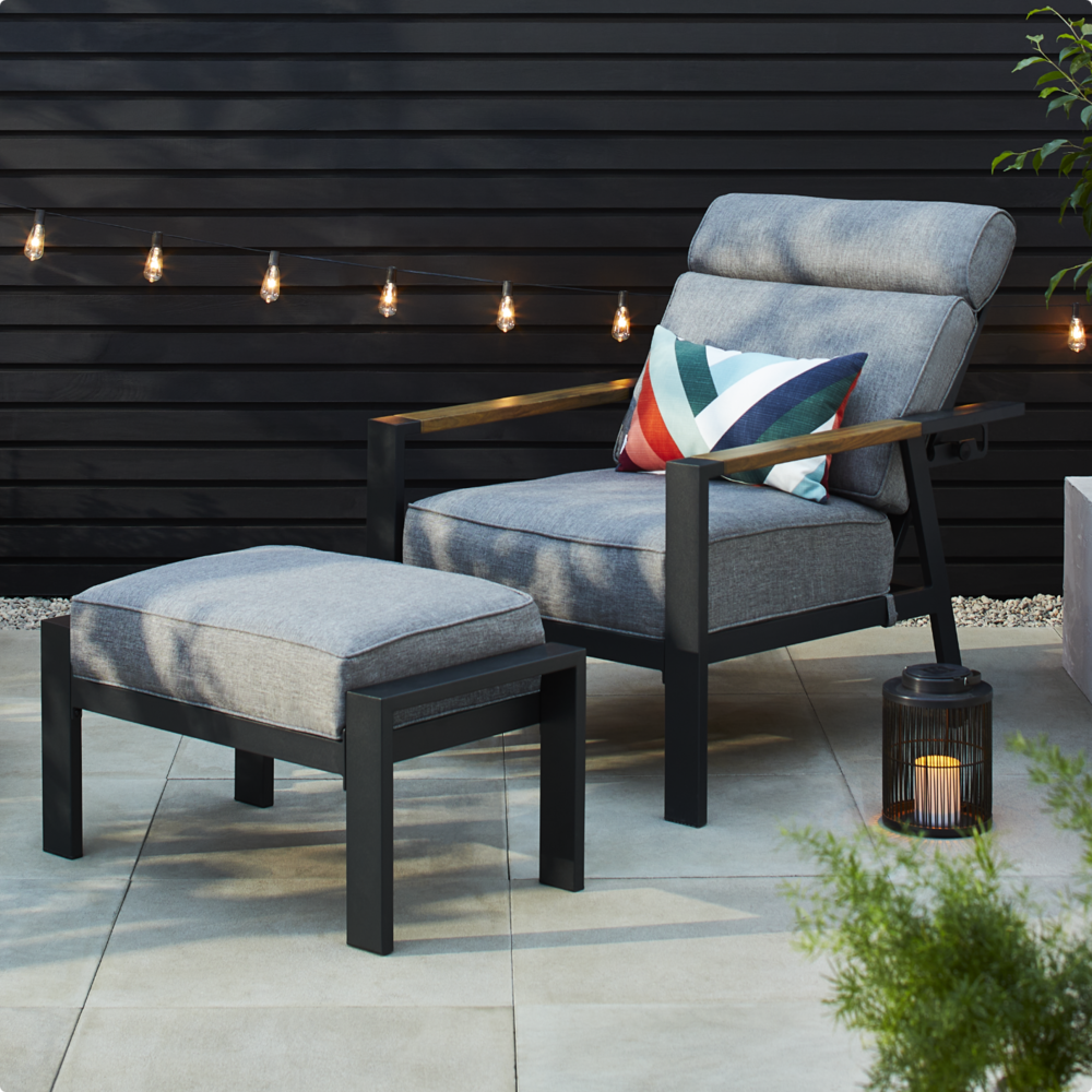 CANVAS Caswell Chair on backyard with footrest and lantern. 