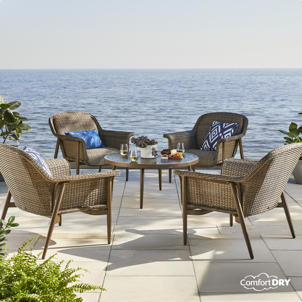 CANVAS Hunter Padded Dining Set on lakeside patio with wicker dining chairs and glasstop table. 