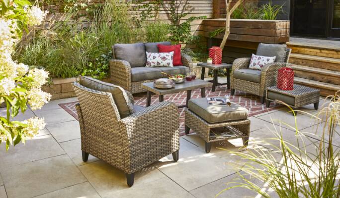 Causeuse, fauteuils, pouf et tables d'appoint de la collection CANVAS Breton installés sur une terrasse.