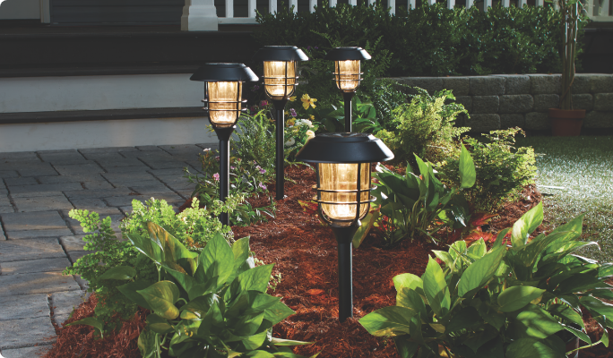 NOMA Solar Flame Touch Stake Lights on driveway garden area. 