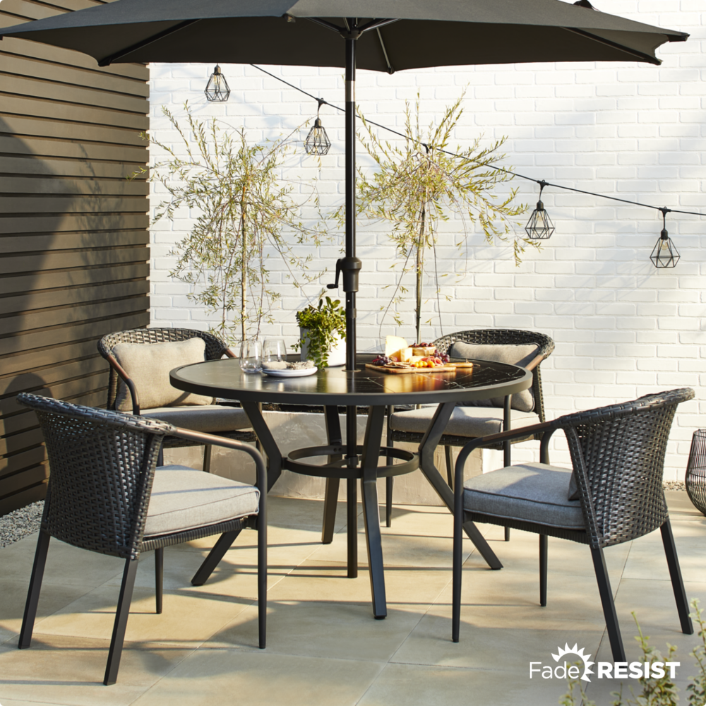 CANVAS Jasper Dining Collection on patio with CANVAS String Lights and umbrella.