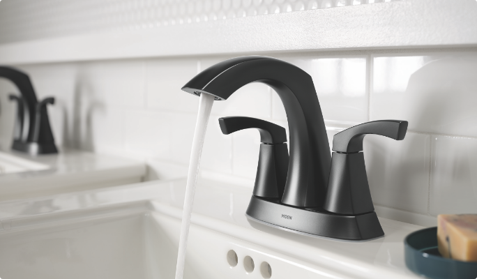 A matte finish dark grey Moen faucet in a bathroom.