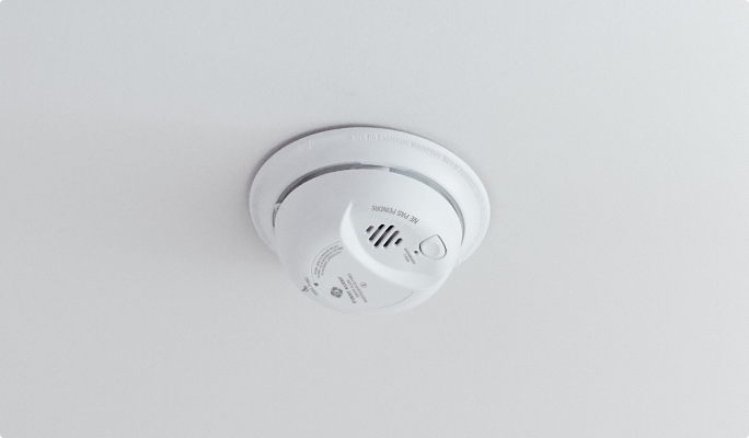 A Kidde smoke detector mounted on a white ceiling.