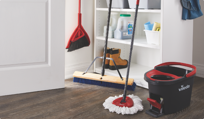 Vileda mop and bucket, angle broom, and Mastercraft push broom in a mudroom.