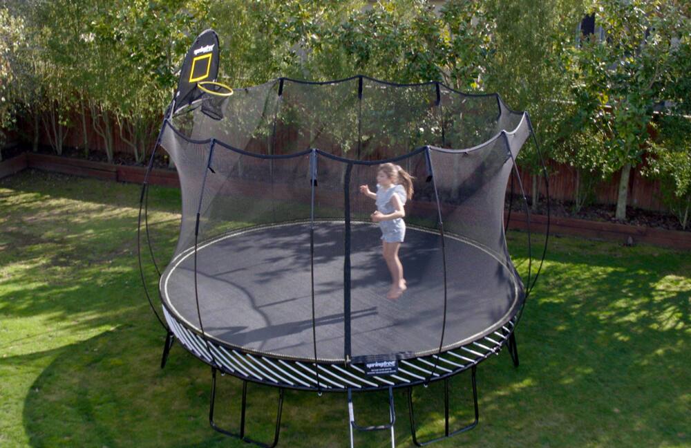 A young girl jumping in a composite trampoline enclosed with netting
