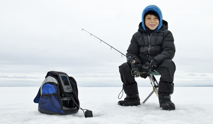 Youth sitting on the icy lake during a fish finder to locate bait.  