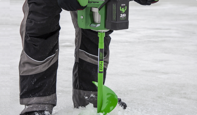 Une personne utilisant une tarière à glace ION sur le lac pendant la saison de la pêche blanche. 
