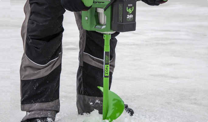 Person using ION ice drill on lake during winter fishing season. 