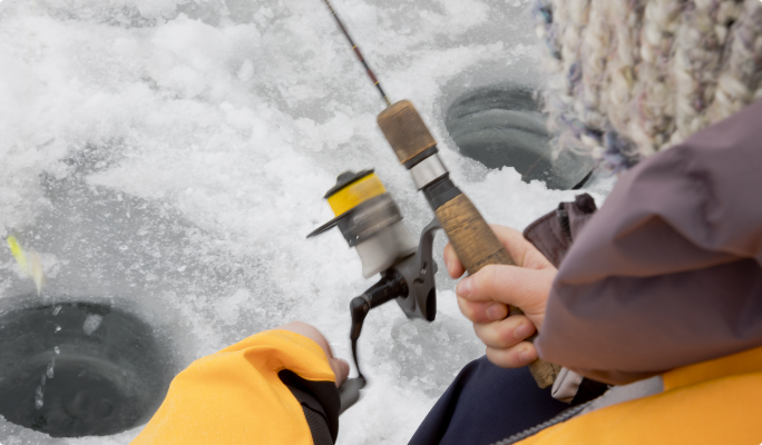 Une personne tenant une canne à pêche sur un lac glacé.