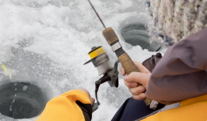 Person holding fishing rod on icy lake.