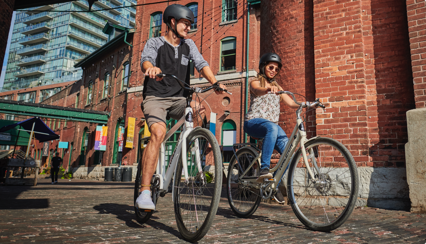 A person rides a Raleigh bicycle on a sunny street.